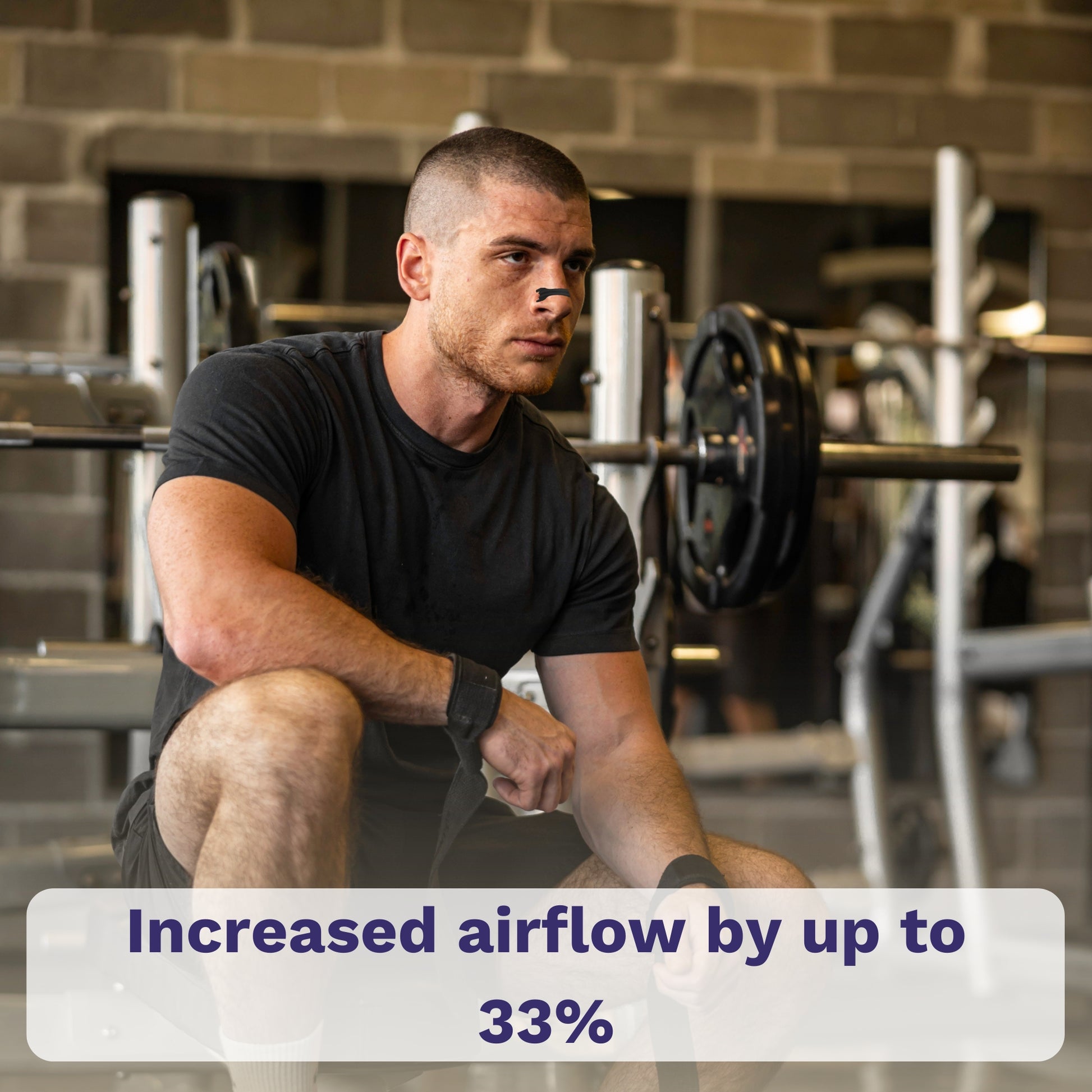 Man resting in gym wearing black nasal strip.