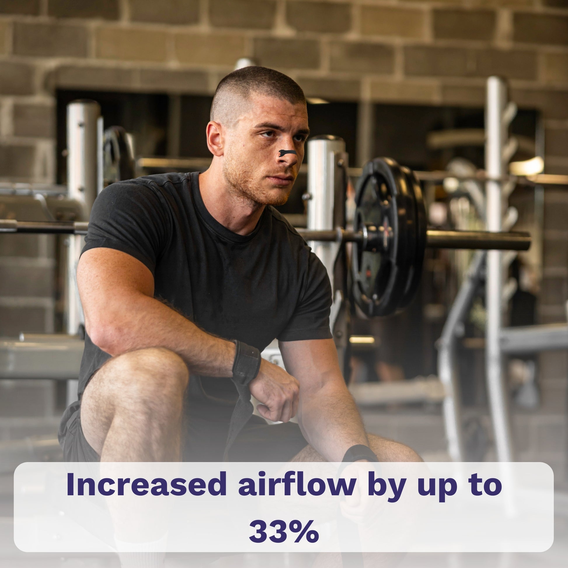 Man resting in gym wearing black nasal strip.